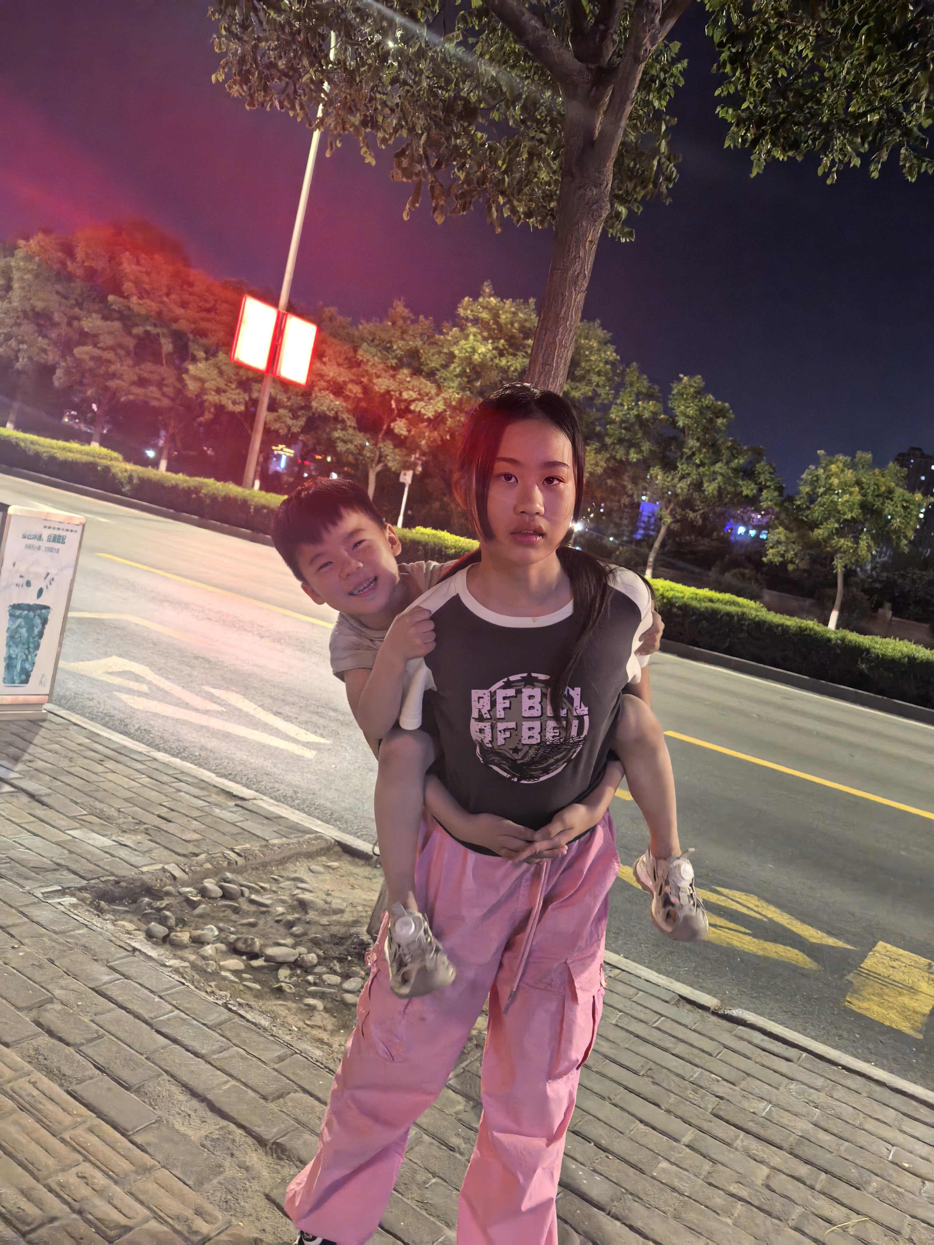 冯艺萱在夜晚街边背着弟弟